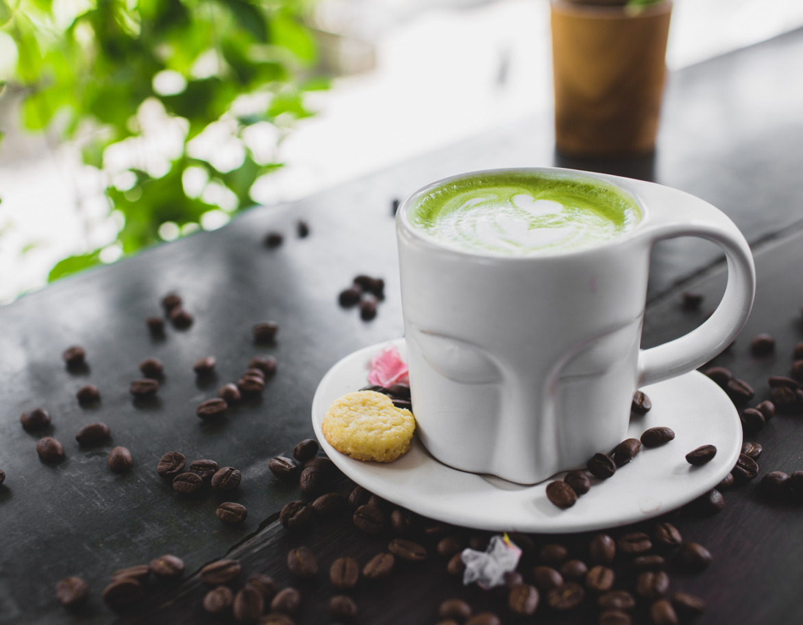 Чашка зеленого кофе с молочными каплями на поверхности